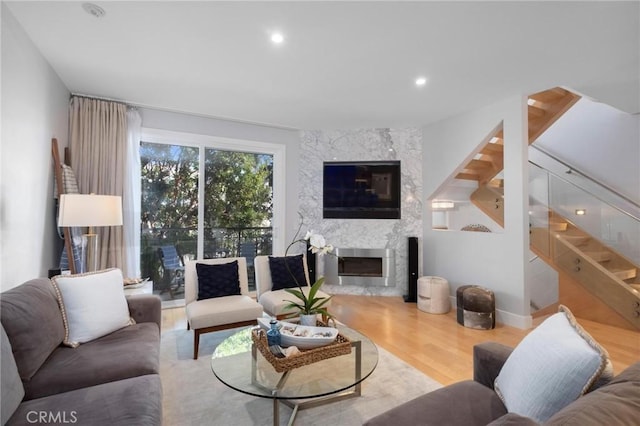 living room featuring recessed lighting, stairway, wood finished floors, and a high end fireplace