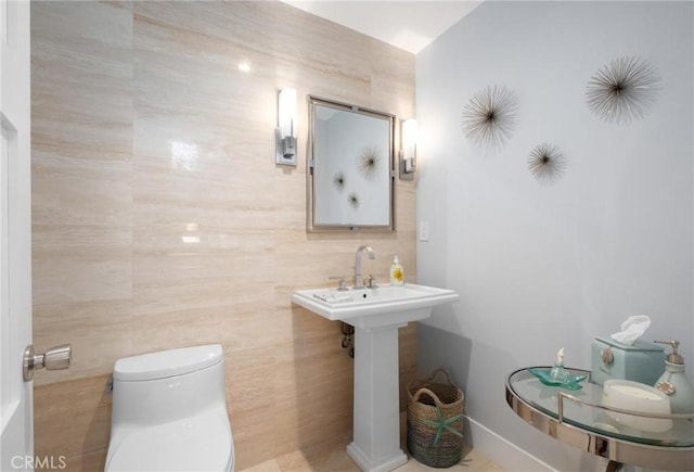 half bath featuring toilet and tile walls