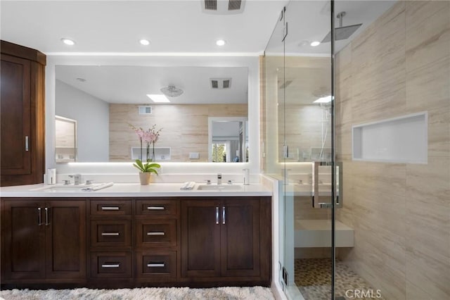 bathroom featuring double vanity, visible vents, a shower stall, and a sink