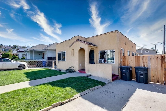 mediterranean / spanish-style house featuring fence private yard, a front yard, cooling unit, and stucco siding