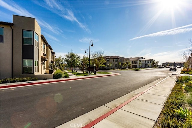 view of road featuring street lighting, a residential view, curbs, and sidewalks