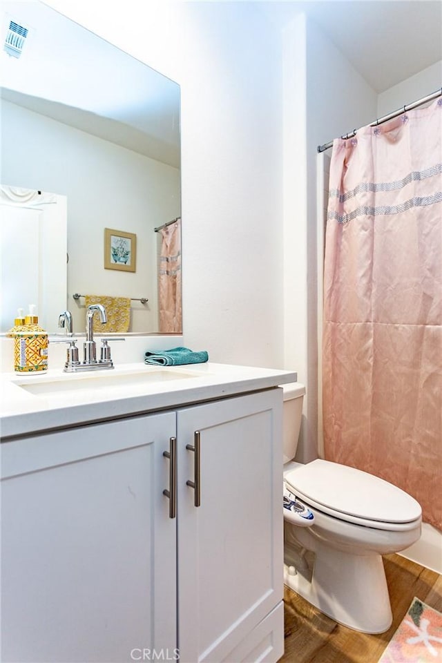 full bath featuring toilet, visible vents, wood finished floors, and vanity