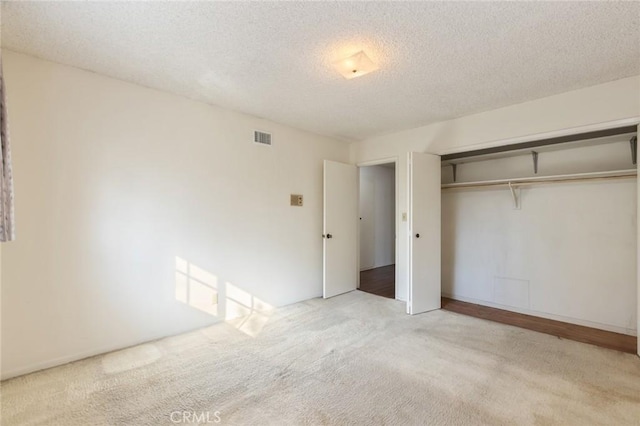 unfurnished bedroom with a closet, visible vents, a textured ceiling, and carpet flooring