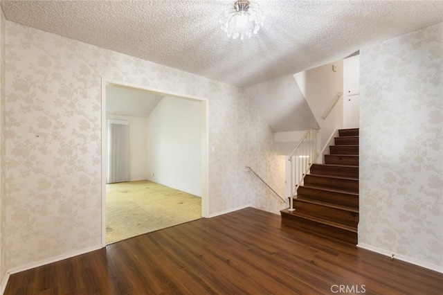 interior space featuring wood finished floors, a textured ceiling, and wallpapered walls