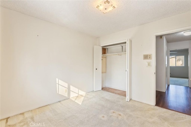 unfurnished bedroom featuring a textured ceiling, a closet, and carpet