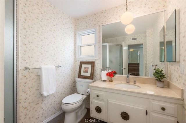 full bathroom featuring wallpapered walls, baseboards, toilet, vanity, and a shower stall