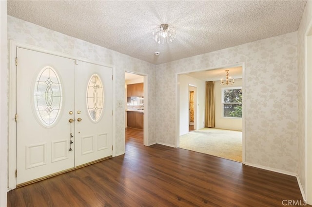 entrance foyer with a chandelier, wood finished floors, a textured ceiling, and wallpapered walls