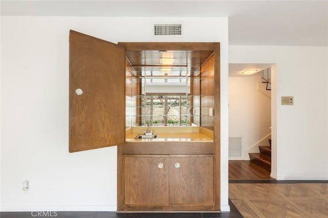 bar featuring stairway, visible vents, indoor wet bar, and a sink