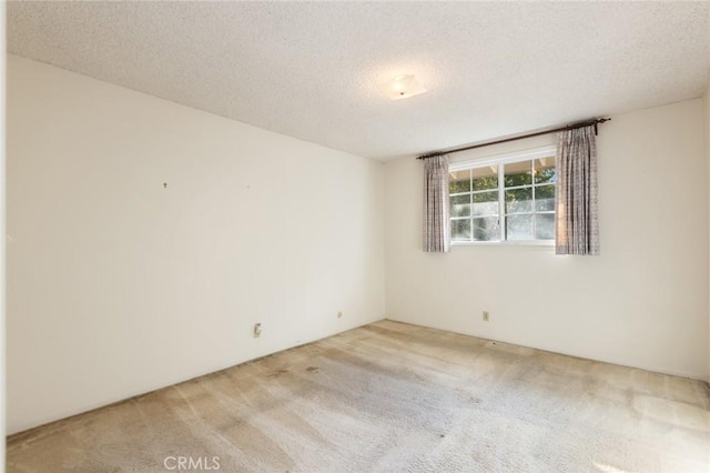 spare room with light carpet and a textured ceiling