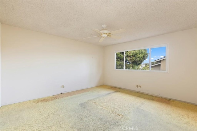 carpeted empty room with a ceiling fan and a textured ceiling