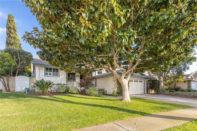 obstructed view of property with an attached garage, fence, driveway, a gate, and a front yard