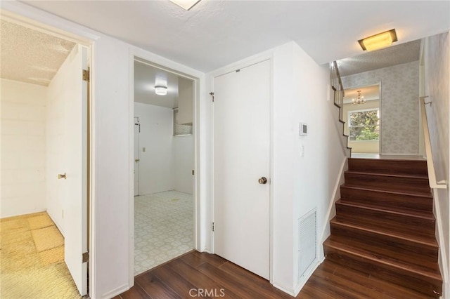 stairway featuring a textured ceiling, wood finished floors, and visible vents