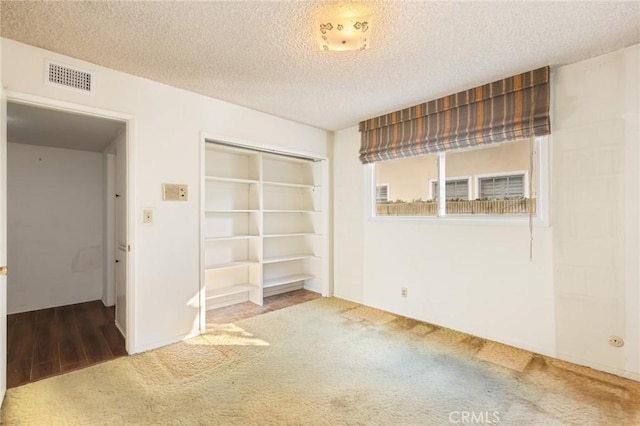 carpeted empty room with visible vents and a textured ceiling