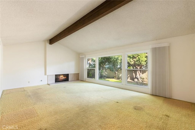 unfurnished living room featuring lofted ceiling with beams, a lit fireplace, a textured ceiling, and carpet flooring