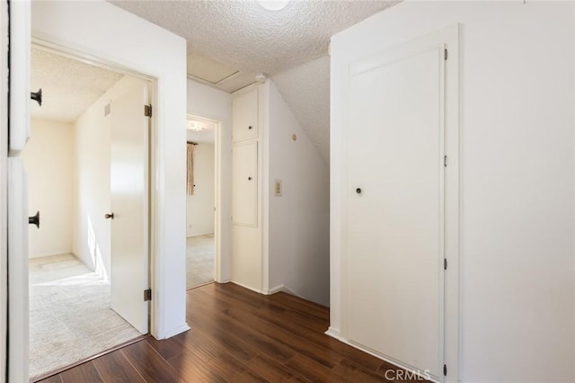 hall with dark wood-style floors, attic access, and a textured ceiling