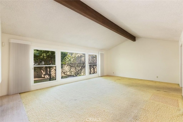 empty room with carpet flooring, lofted ceiling with beams, and a textured ceiling