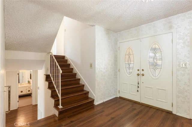 entryway with a textured ceiling, dark wood finished floors, and wallpapered walls