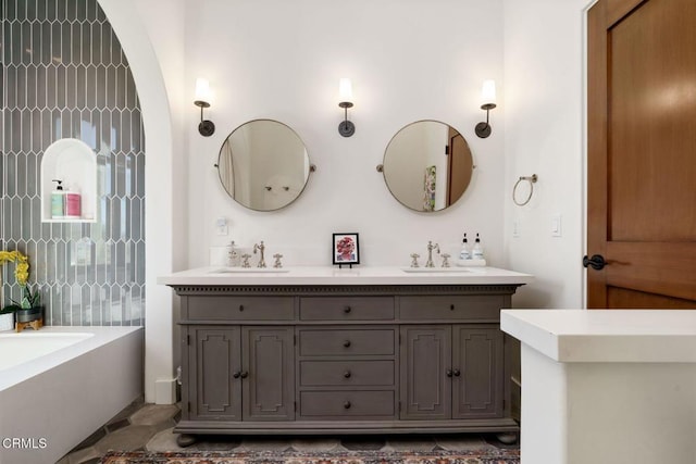 full bathroom with double vanity, a washtub, and a sink