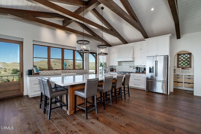 kitchen with dark wood-style floors, tasteful backsplash, high end fridge, light countertops, and premium range hood