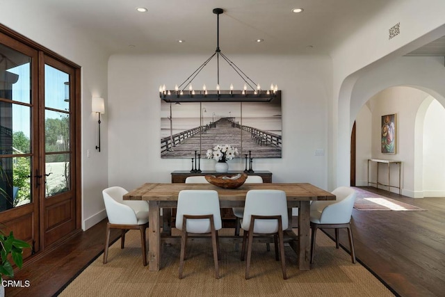 dining space featuring arched walkways, recessed lighting, wood finished floors, a chandelier, and baseboards