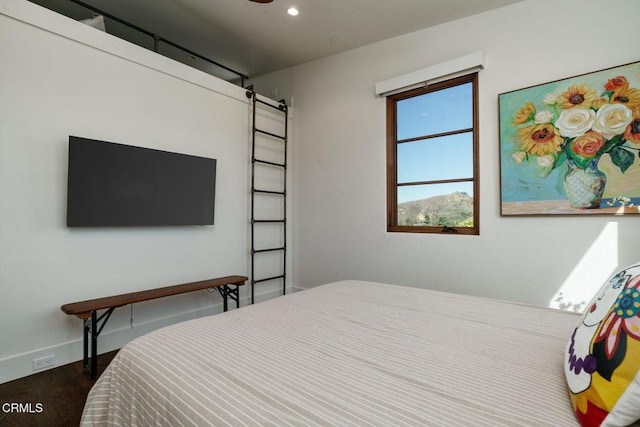 bedroom with baseboards, a barn door, wood finished floors, and recessed lighting