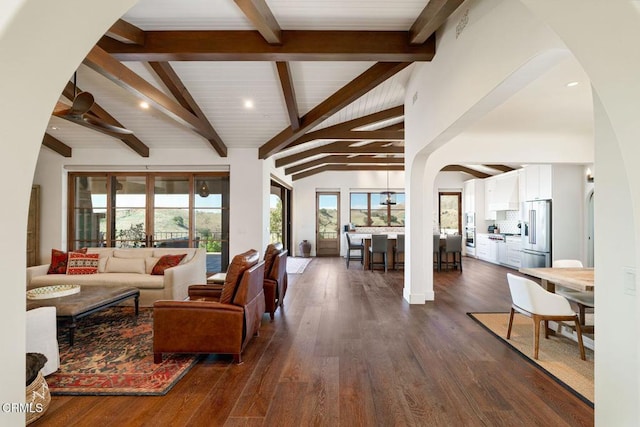 living room with arched walkways, high vaulted ceiling, dark wood-style flooring, and beam ceiling