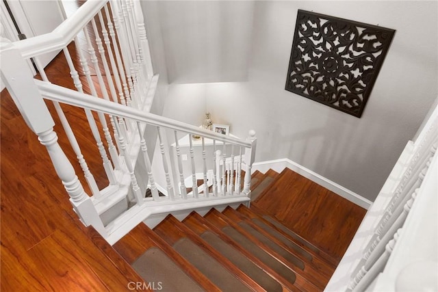 staircase with baseboards and wood finished floors