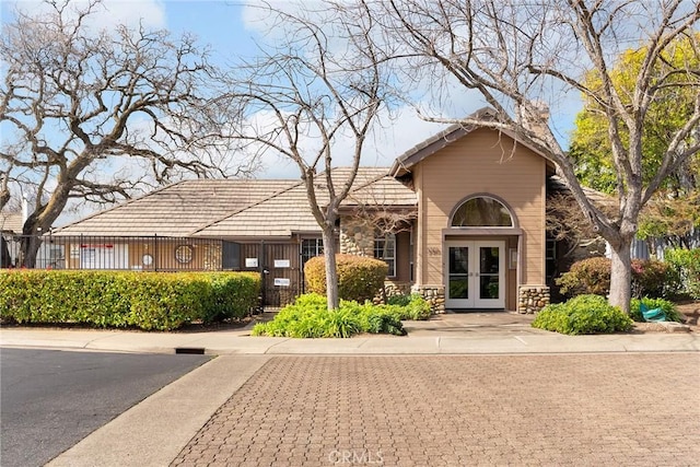 view of front of property with stone siding, french doors, and a tiled roof