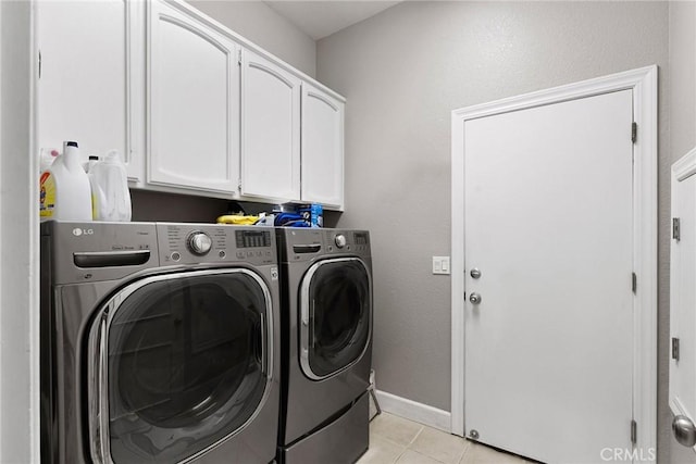 clothes washing area with cabinet space, light tile patterned floors, baseboards, and independent washer and dryer