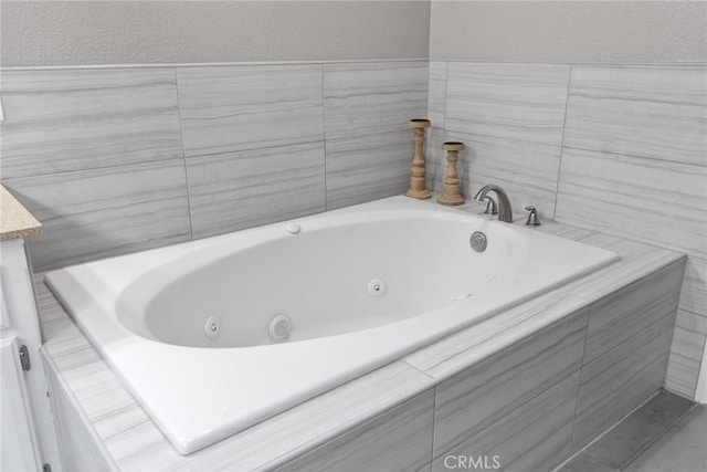 bathroom featuring a textured wall and a tub with jets