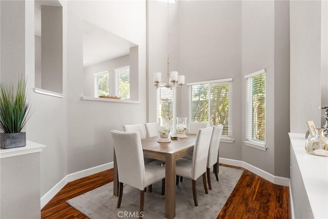 dining area featuring wood finished floors, a healthy amount of sunlight, baseboards, and an inviting chandelier