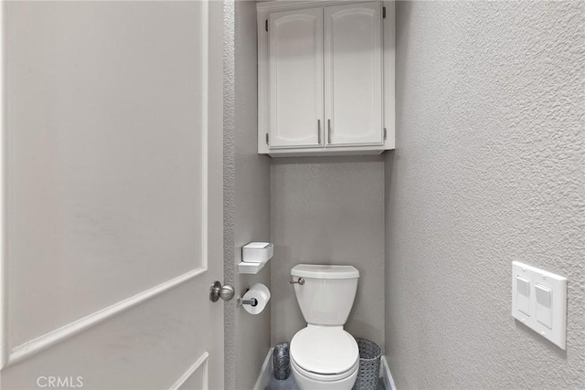 bathroom with a textured wall and toilet