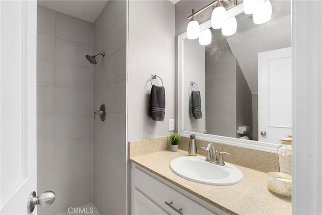 full bathroom featuring tiled shower and vanity