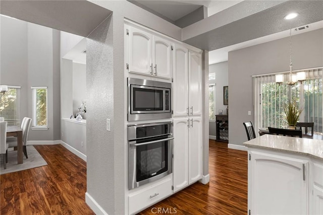 kitchen with appliances with stainless steel finishes, a chandelier, and white cabinetry