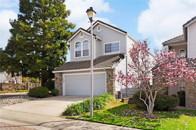 traditional home featuring a garage, stone siding, a tile roof, and driveway