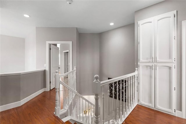 hall featuring baseboards, wood finished floors, an upstairs landing, and recessed lighting