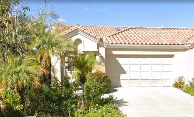 mediterranean / spanish-style house featuring stucco siding, a garage, driveway, and a tiled roof