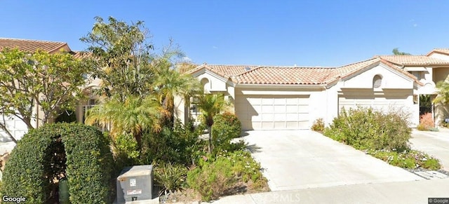 view of front of house featuring a tiled roof, stucco siding, an attached garage, and driveway