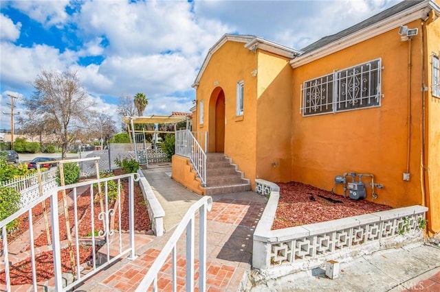 property entrance with fence and stucco siding