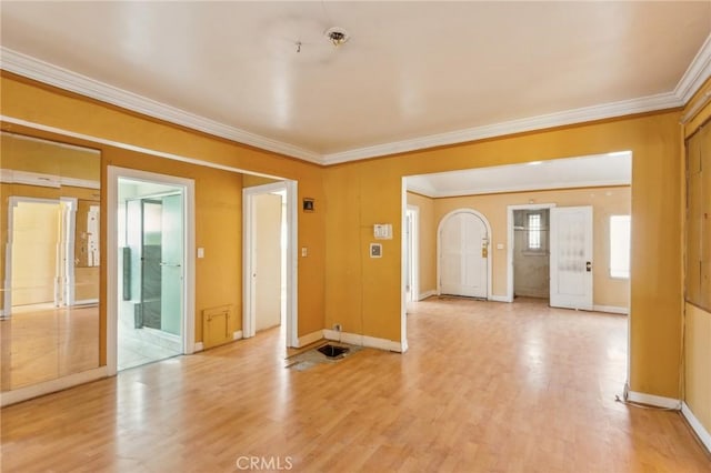 empty room featuring ornamental molding, light wood-type flooring, and baseboards