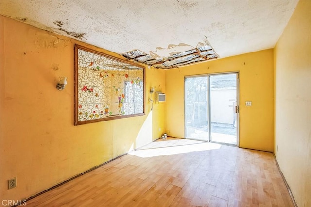 spare room with an AC wall unit and wood finished floors