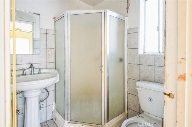 full bathroom featuring toilet, tile walls, and a shower stall