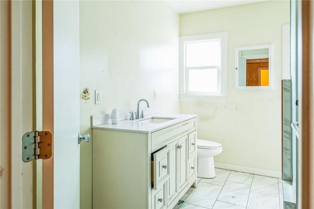 bathroom featuring toilet, baseboards, and vanity