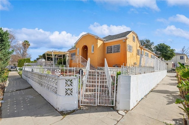 view of front of property with a fenced front yard, a gate, and stucco siding