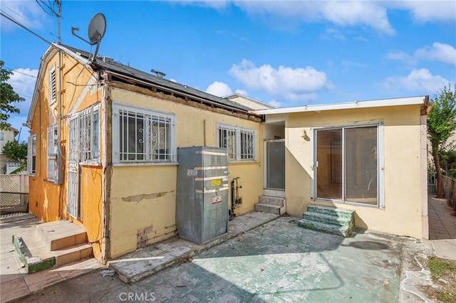 back of property featuring entry steps, fence, and stucco siding