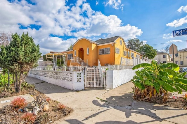 view of front facade with a fenced front yard, a gate, and stucco siding