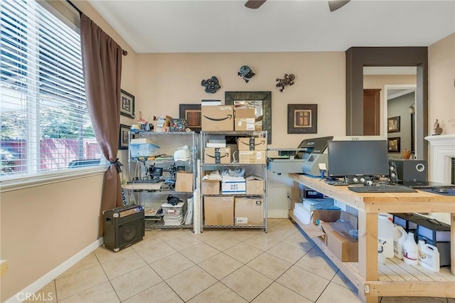 office area with a ceiling fan, a fireplace, baseboards, and tile patterned floors