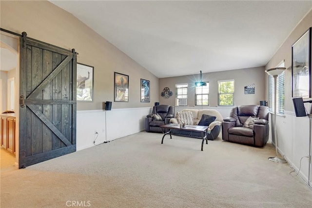 living room featuring lofted ceiling, carpet flooring, and a barn door