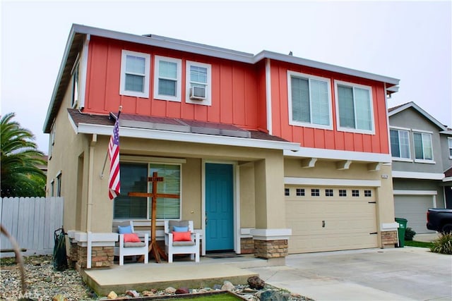 view of front of house featuring a garage, driveway, covered porch, fence, and board and batten siding