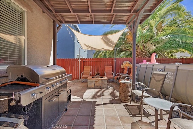 view of patio with an outdoor fire pit, area for grilling, and a fenced backyard